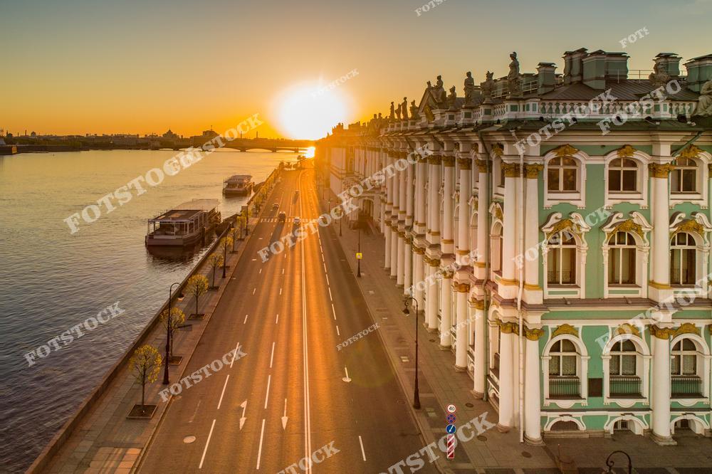 Панорамная фотография Санкт-Петербурга на рассвете, снятая с высоты птичьего полета. На снимке запечатлены Эрмитаж, Дворцовая набережная, река Нева и улицы исторического центра города. Мягкий утренний свет подчеркивает красоту архитектуры Северной столицы России, отражения на воде и атмосферу спокойного начала дня. Вид с дрона позволяет увидеть масштаб городского пространства, величественные здания музеев и гармоничное сочетание рек, улиц и исторических ансамблей. Фотография идеально подходит для туристических публикаций, фотостоков, оформления интерьеров, рекламы и материалов о культуре и достопримечательностях Санкт-Петербурга.